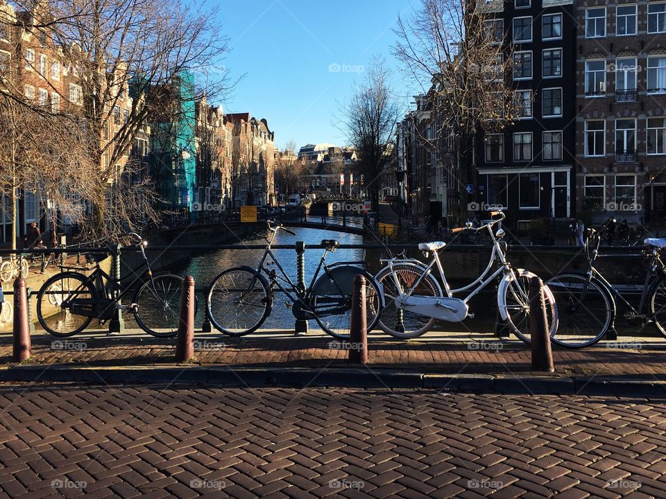 Bicycles lean against a wrought iron railing on a picturesque bridge in central Amsterdam. 