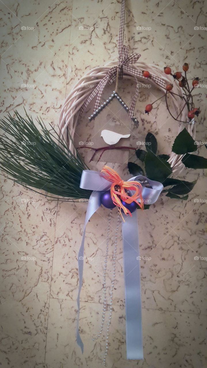 winter holiday decoration Christmas wreath with evergreen pine blue balls orange ribbon and wooden bird in home