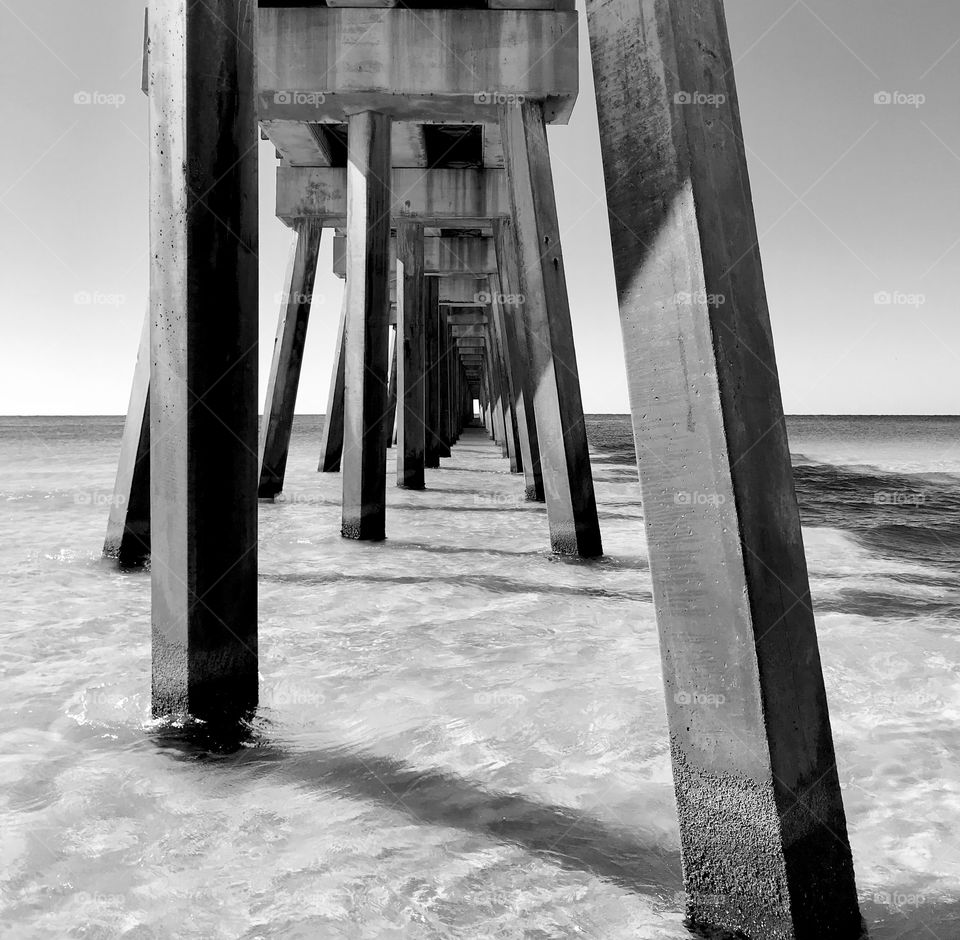 Under the boardwalk on the beach in black and white 