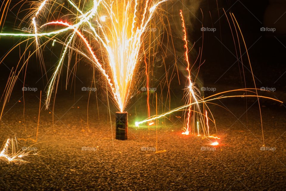 A closeup of a fireworks pot burning up with different kind of colors on NYE