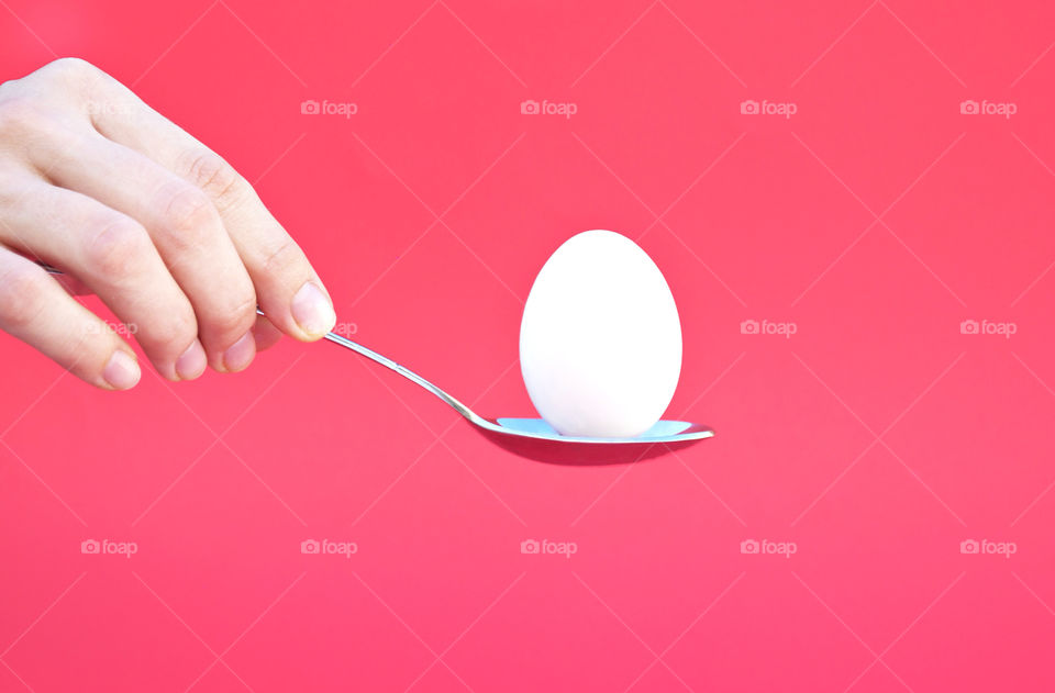 Hand holding an Egg with a spoon