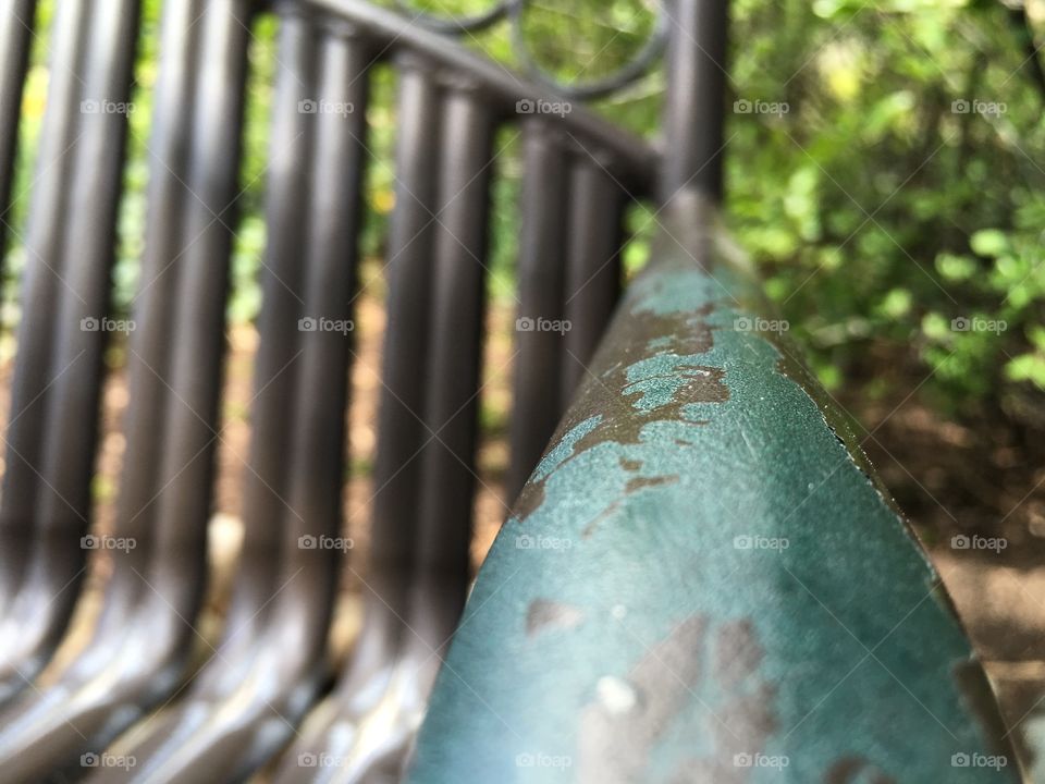 A weathered metal bench in a park