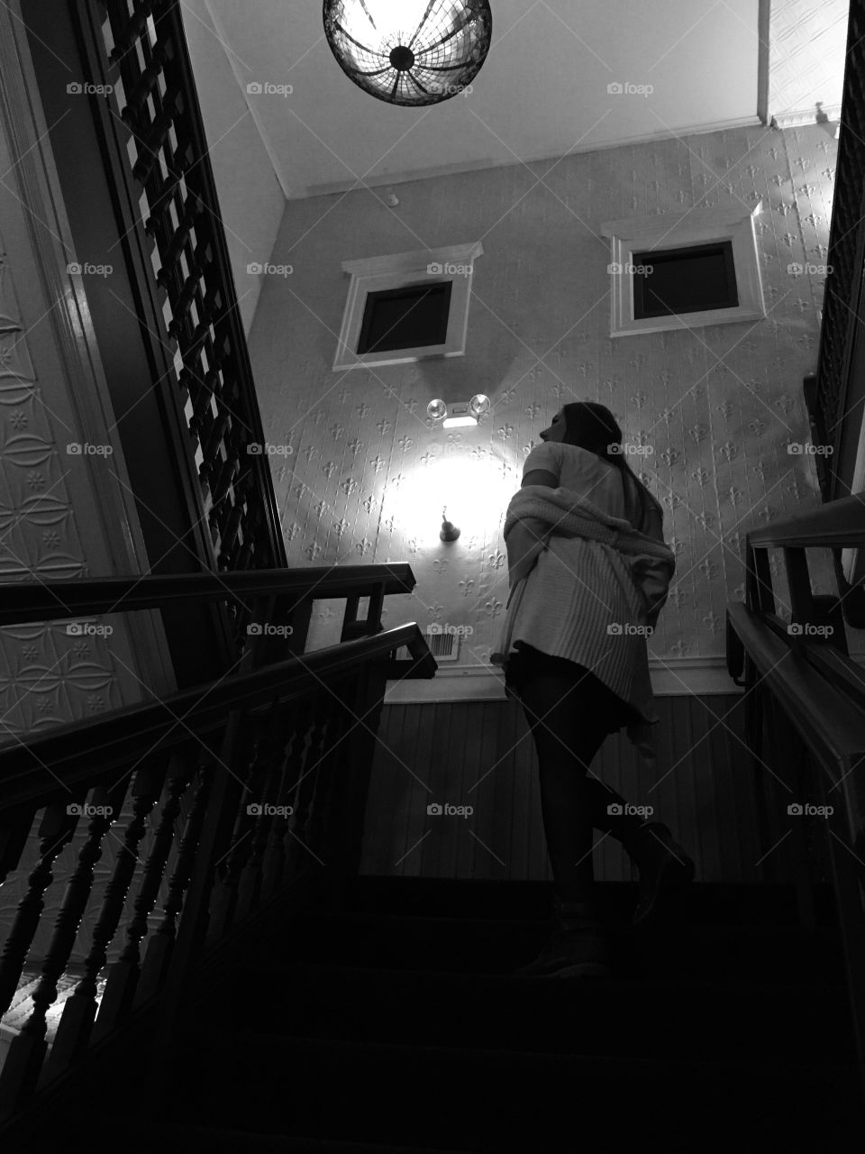 Narrative black and white photo of young woman climbing an old staircase