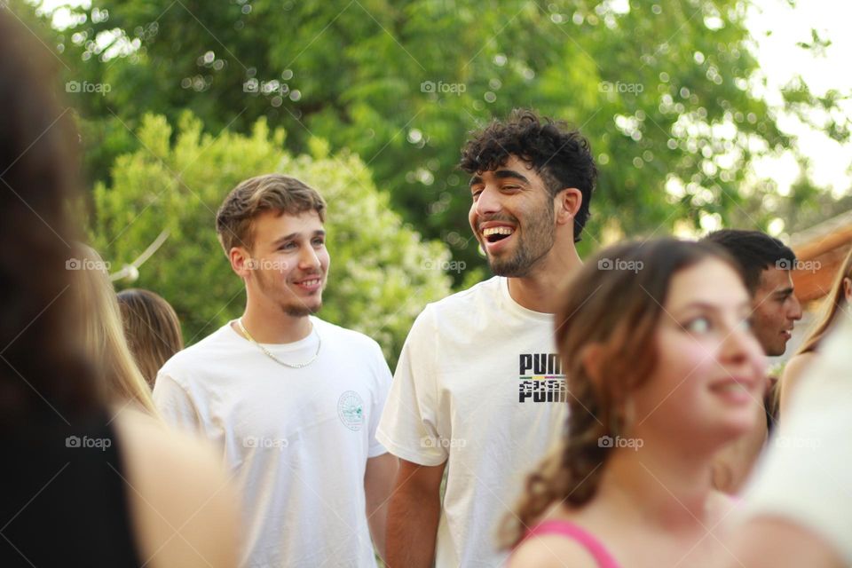 Two men laughing together in the middle of an afternoon party 