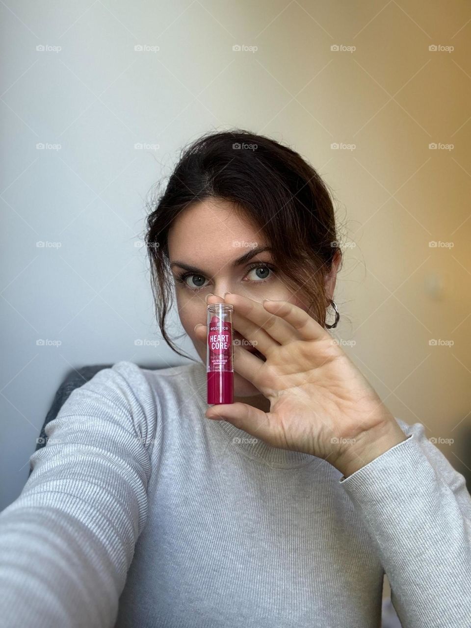 Woman’s portrait with product, girl holding a lipstick in her hands 