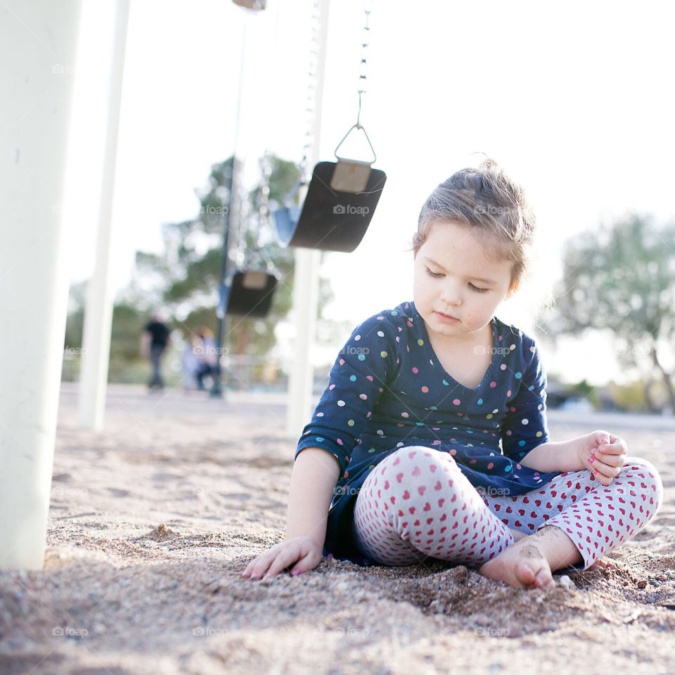 Girl playing in the sand at the playground 