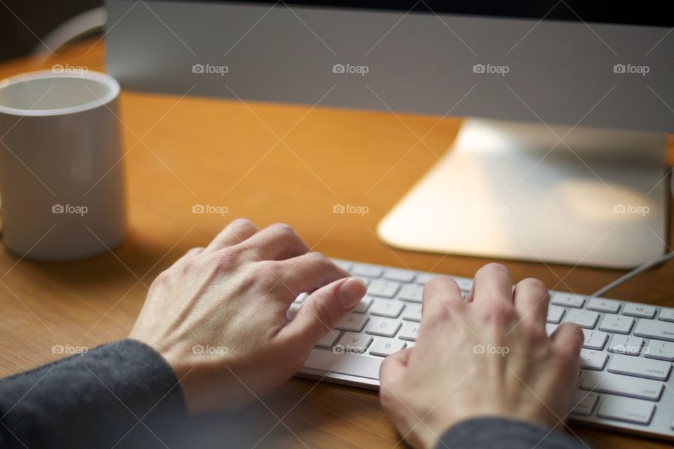 Female hands typing on iMac keyboard.
