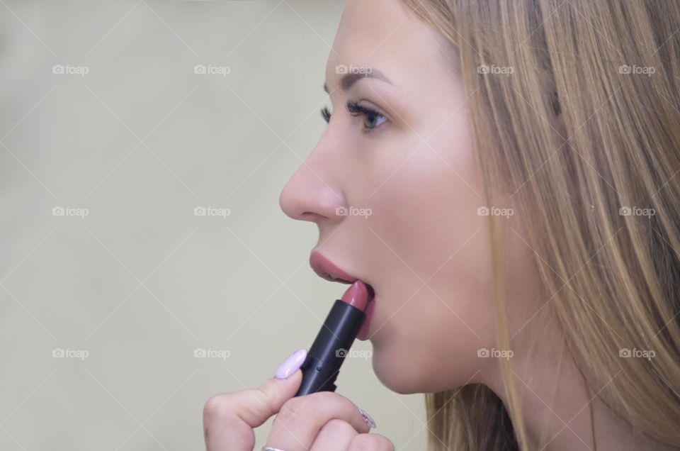 girl paints her lips with lipstick