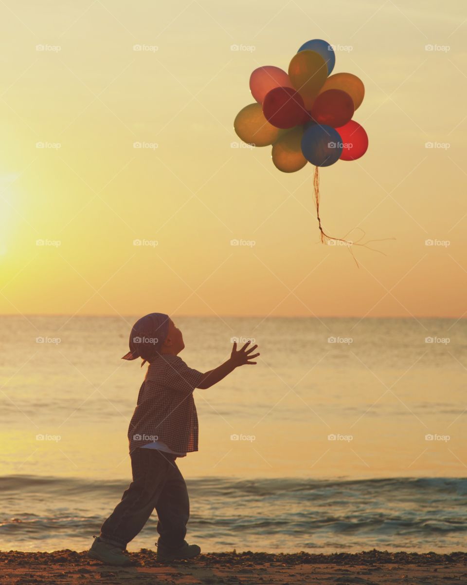 Boy playing on beach with balloons