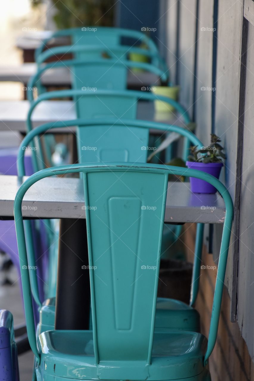 Turquoise chairs, row of bright chairs against a wall at a side walk cafe, perfect line and colorful sight