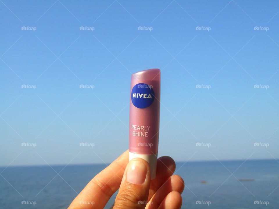 lipstik Nivea in the hand on a sea, vacation product