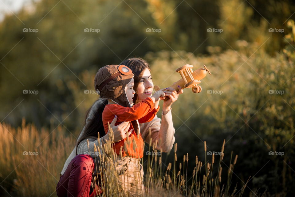 Mother and son with wooden plane at sunset