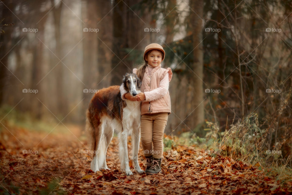 Cute smiling girl with borzoi dog in an autumn park 