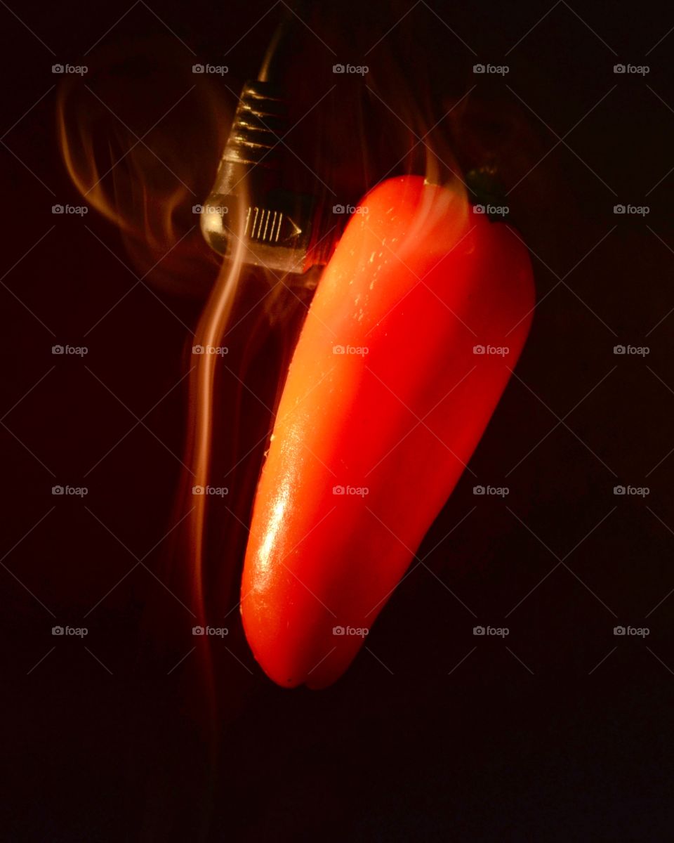 Hot pepper. Hung a pepper from an old phone cord. Looks like the wire is heating the pepper from the inside.