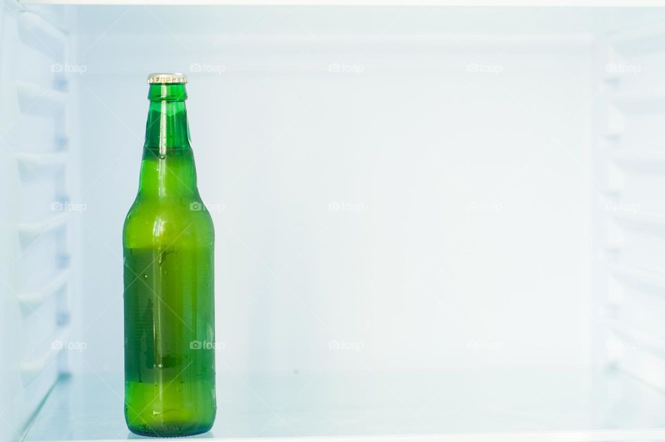 A bottle of beer in the refrigerator. Cold drinks. Minimalism. Green. Copy space 