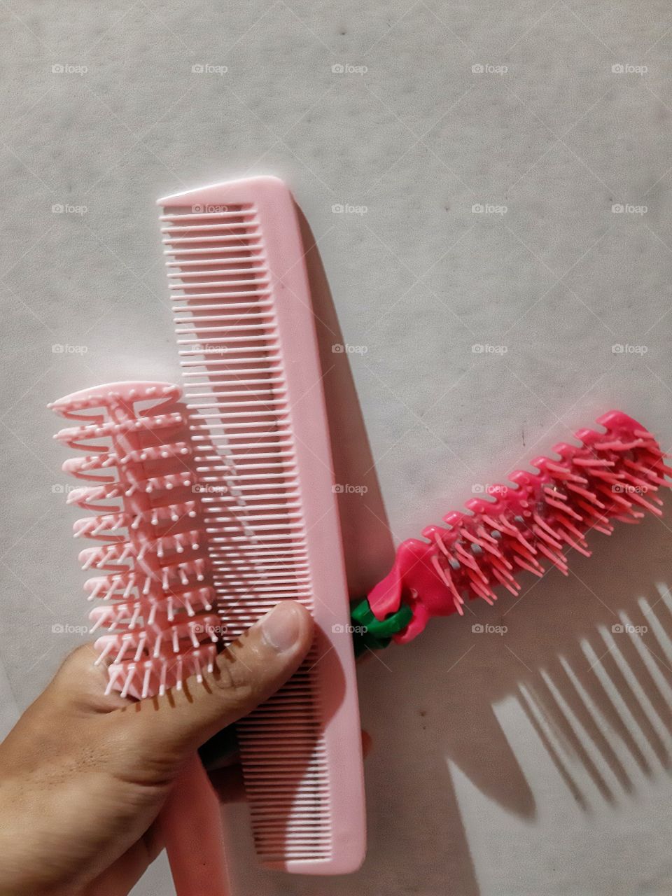 Three pink plastic combs with white background.