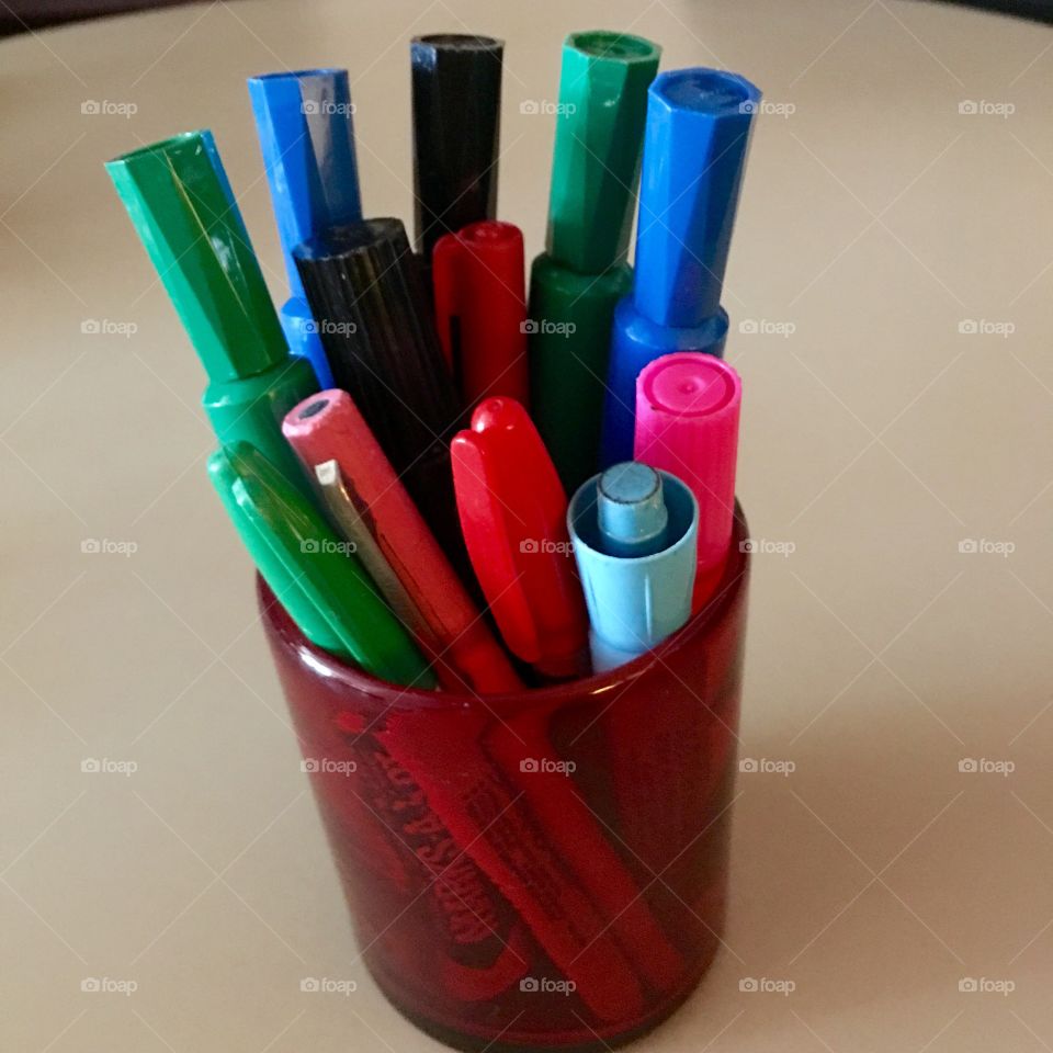 Permanent markers in red glass holder.