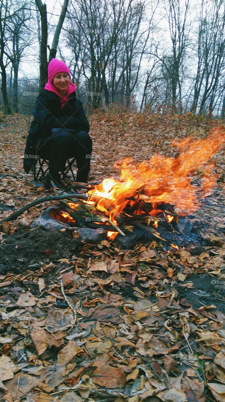 girl sitting by the fire on the nature, autumn 2016