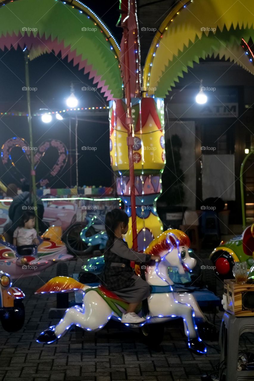 a girl with pretty outfit riding coursel at night