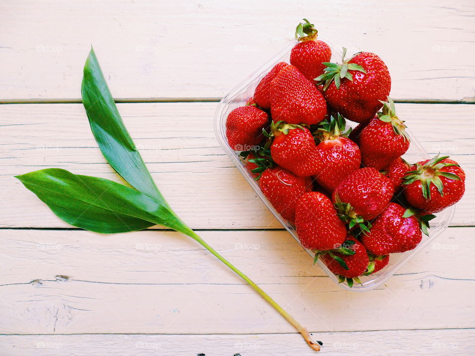 red strawberries and a green leaf on a white background