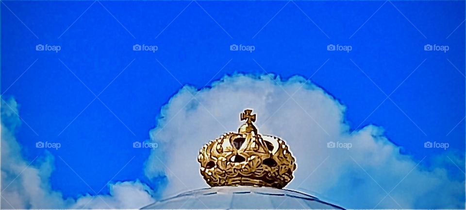 An amazing view of a feathery cloud over a gold rooftop ornament.