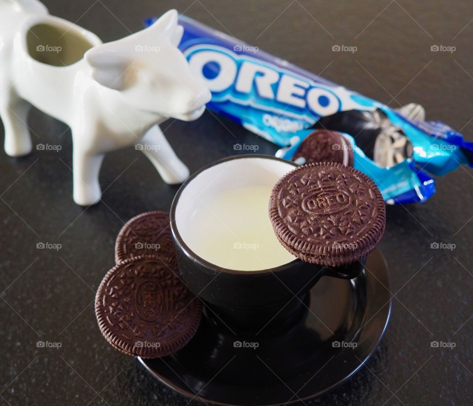 Oreo cookies with cup if milk and cow creamer.