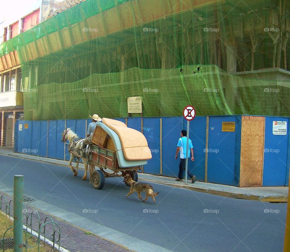 Moving Day. A man moving all his belonging  on a wagon. Family dog tied to the wagon following along. 