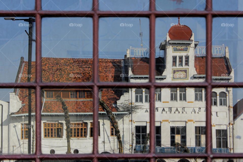 Portrait reflection of a building from the Dutch colonial heritage on a building window framed by wooden windows, namely the European-style maritime museum, Jakarta, Indonesia.