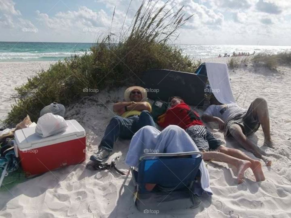 Men  taking  a nap on the sand.