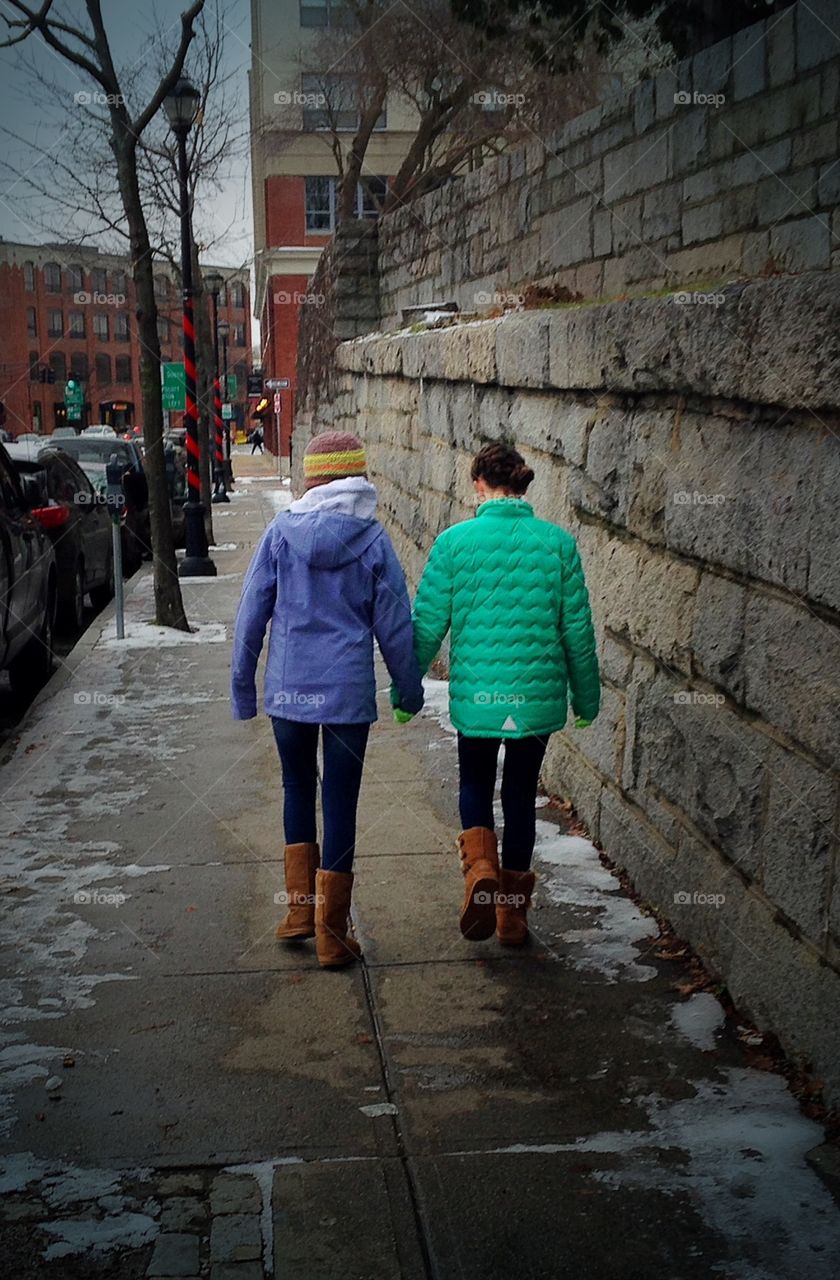 Friends - good friends holding hands so as to not slip and fall on the slippery sidewalk