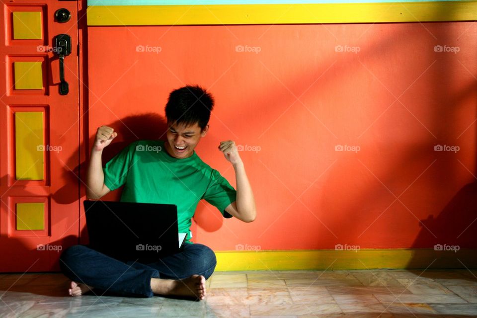 young asian teen with a laptop computer in a living room