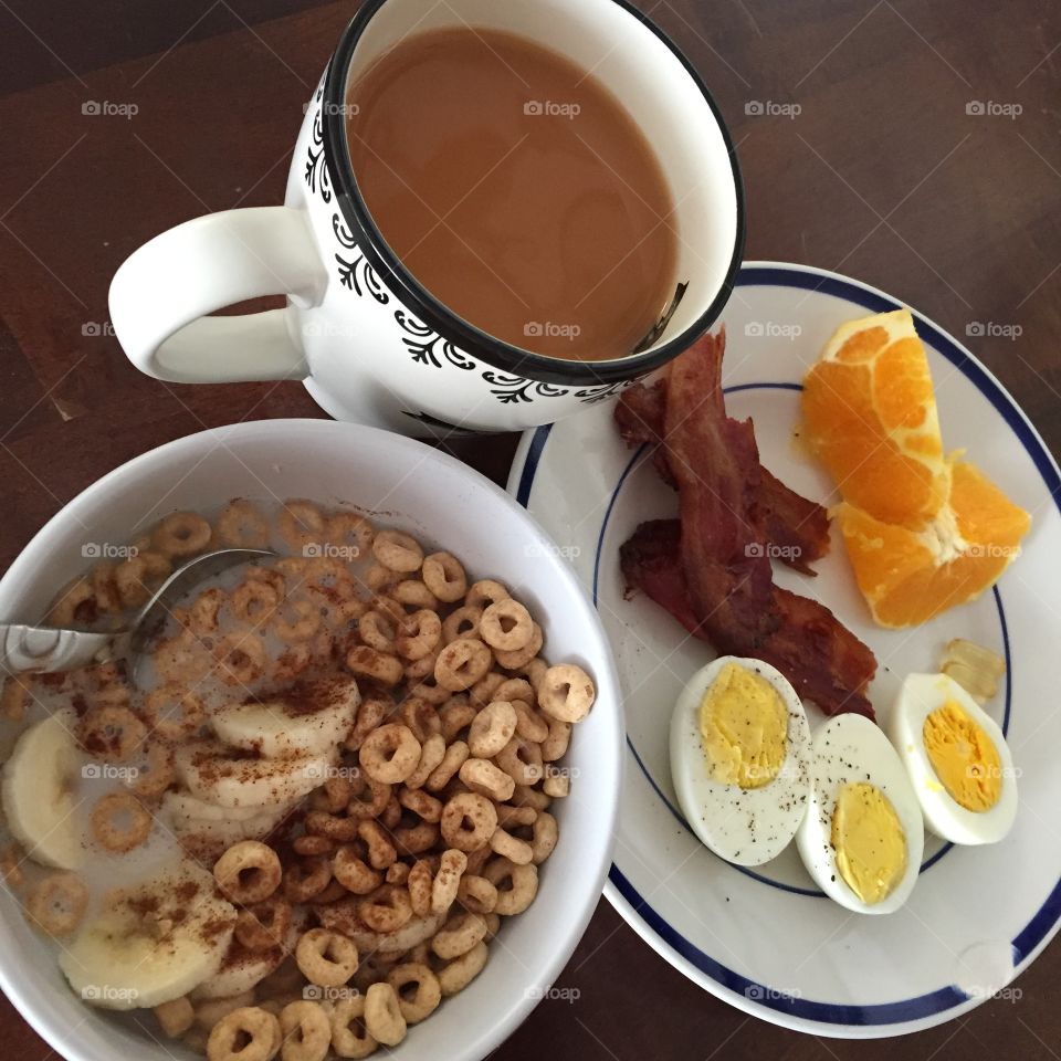 Breakfast is served! Eggs, bacon, cereal, banana, oranges, coffee and vitamins.