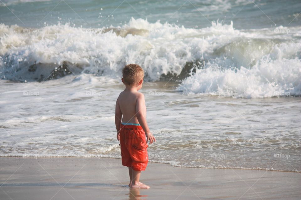 boy child watches waves at beach