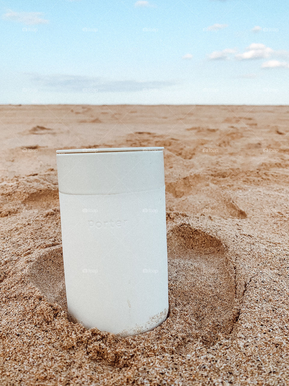 A Porter to-go coffee cup placed in the sand on the beach during morning in Kauai, Hawaii on the west side.