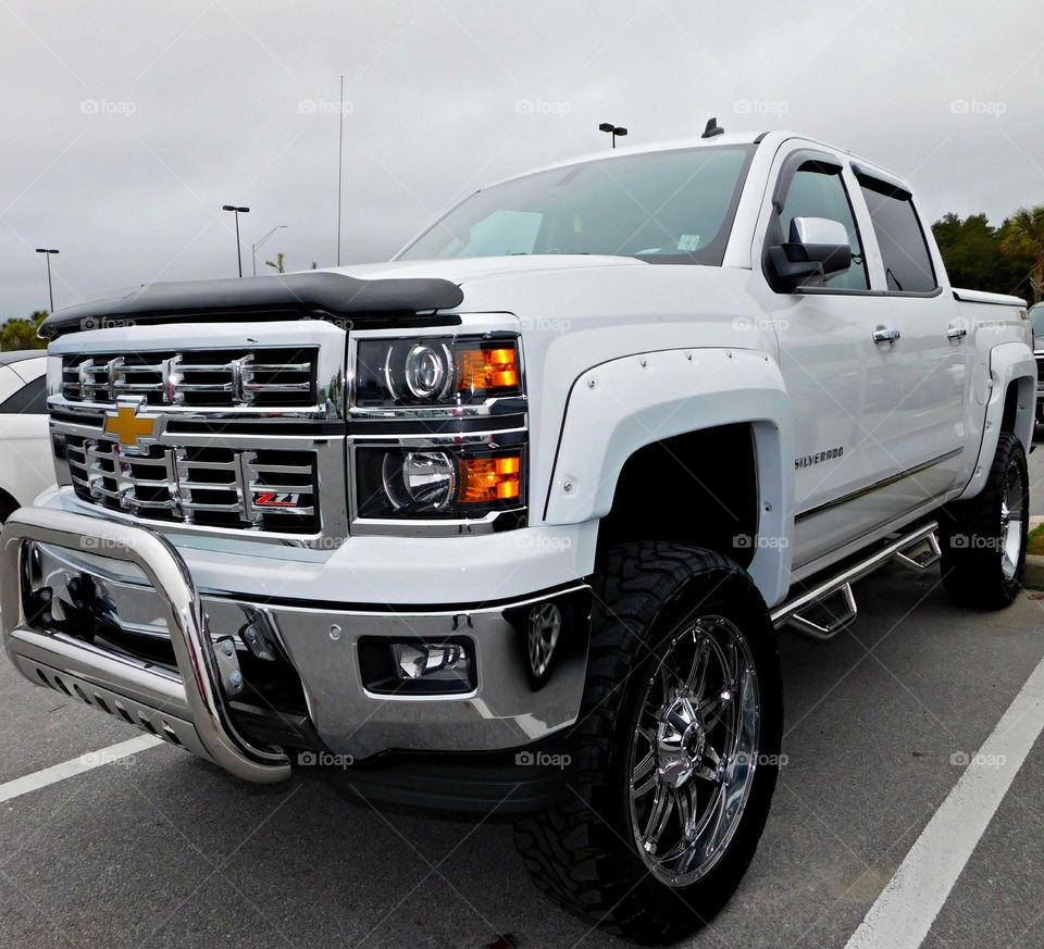 White Chevrolet Silverado Z71 sitting high from the ground. Chromed out around. Super truck