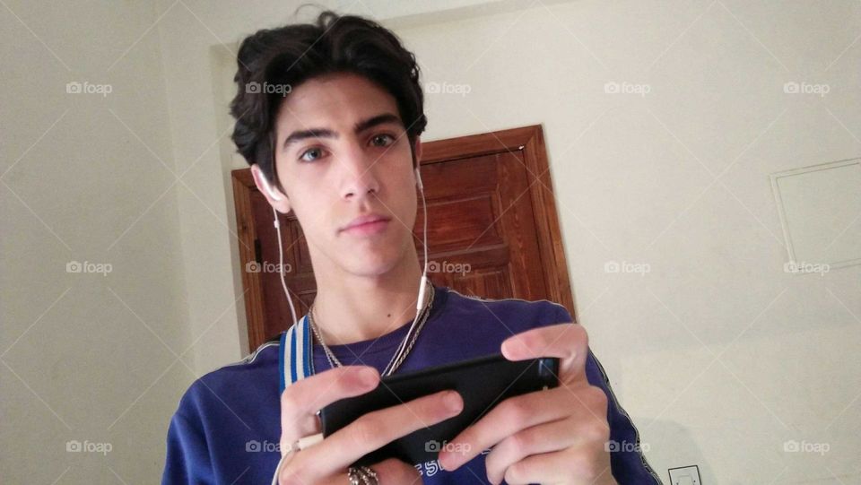 A shaved and young man plays with its phone