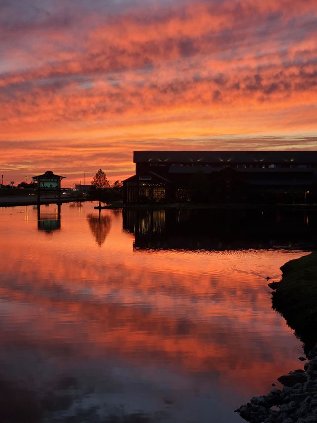 A brilliant Oklahoma sunset is reflected on a lake on a calm summer evening