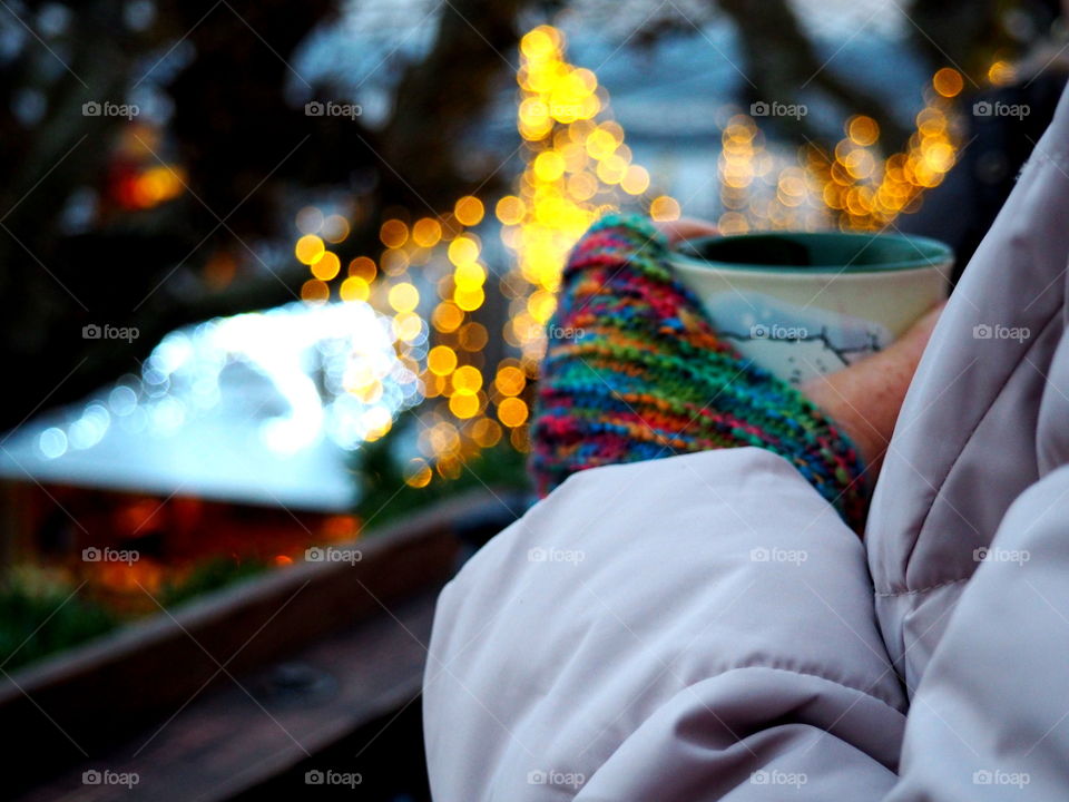 woman with colourful self-made gloves holding a cup with tea on the Christmas market