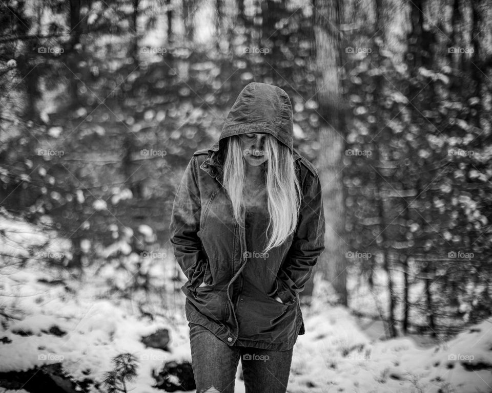 Woman walking through a snowy forest on a cold day; Black and White