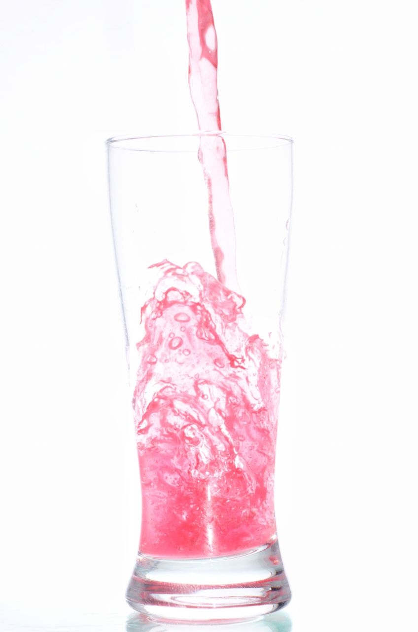 Foto de líquido vermelho caindo em um copo de vidro