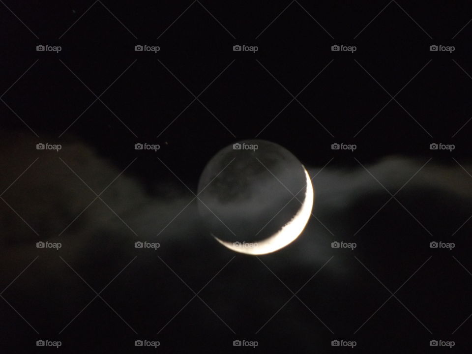 Waxing Crescent moon behind a ribbon of cloud