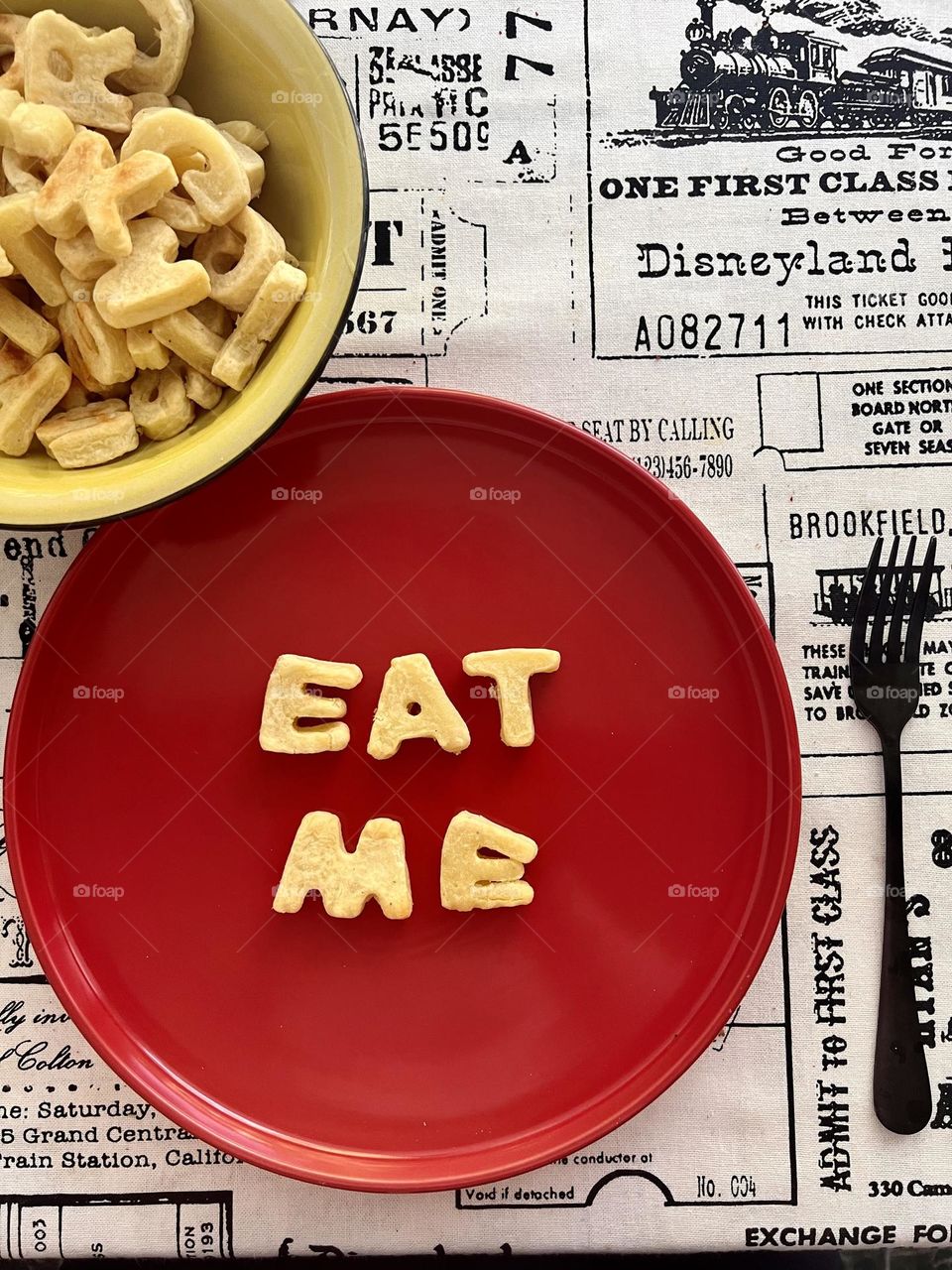 Eat me type made of potatoes shaped alphabet on a red plate