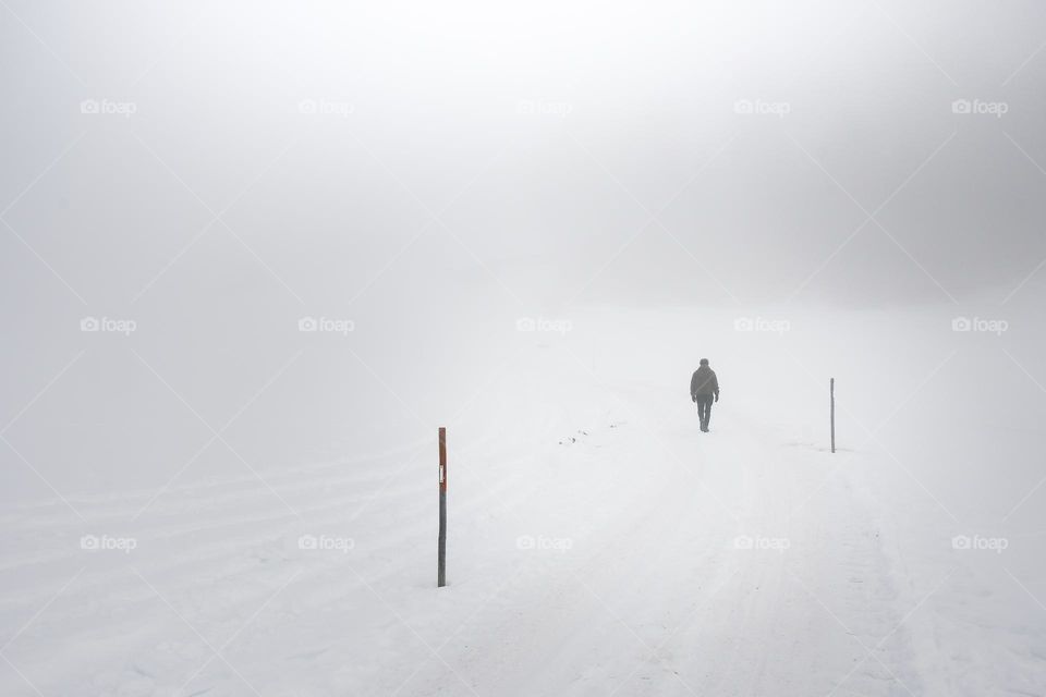 Landscape photo of a man walking in nature during fog or foggy weather and winter