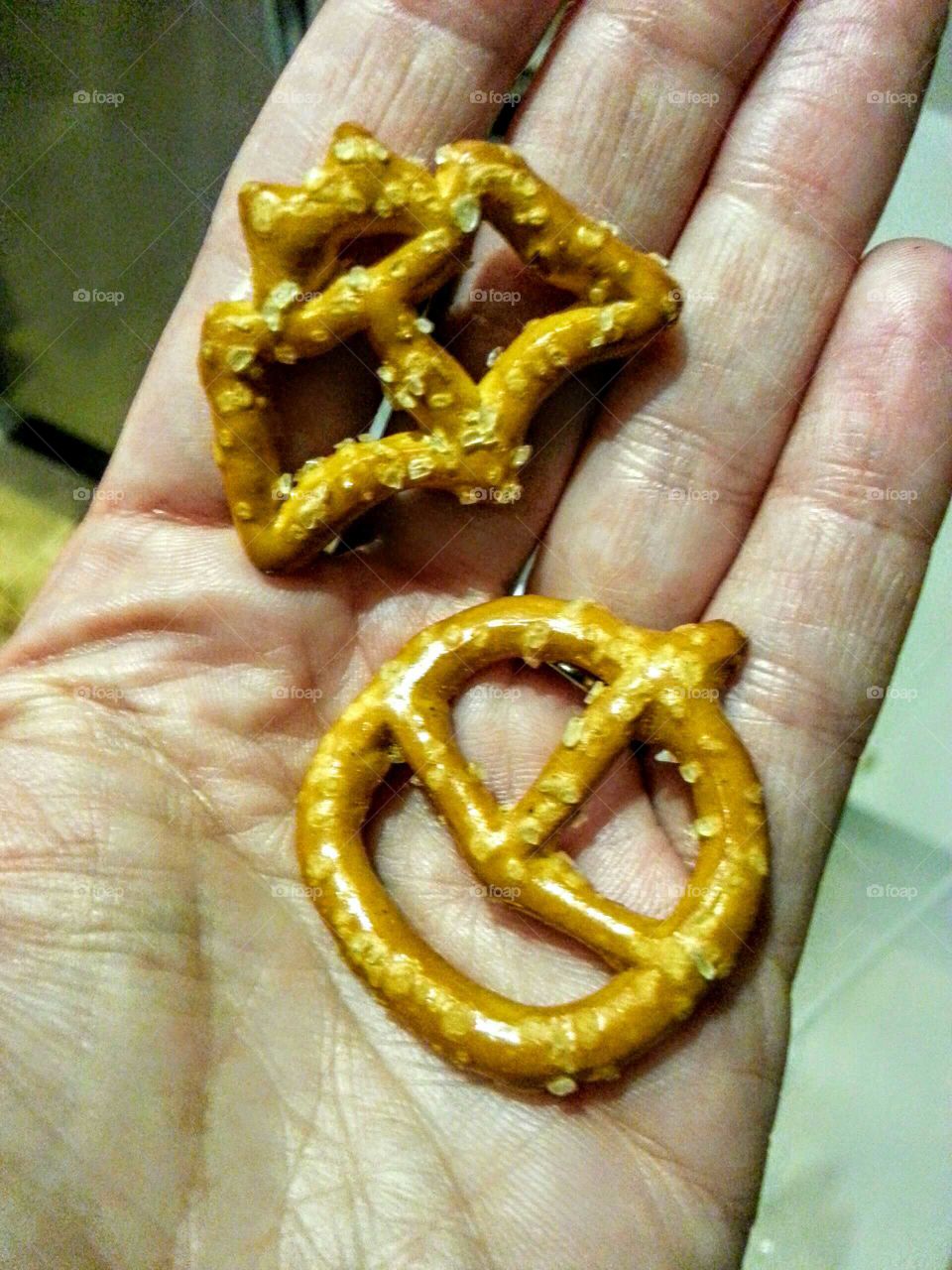 Close-up of a hand holding original shapped pretzels