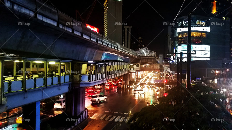 Asoke Cross at night in Bangkok with car rail and train rail along. Seeing Asoke Sky train station from here.