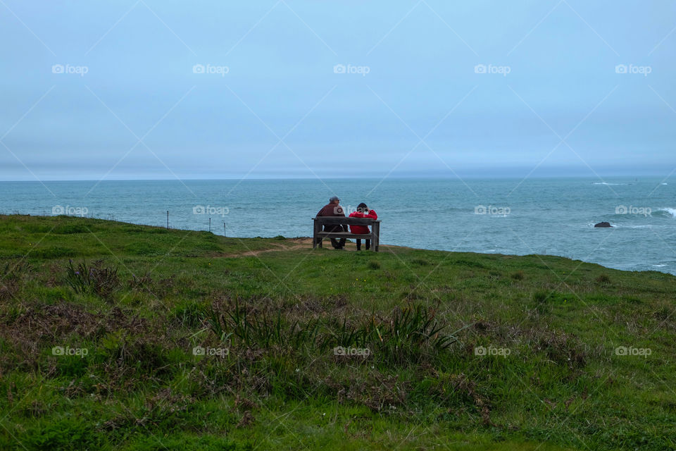 Couple enjoying the ocean view, sitting on a bench