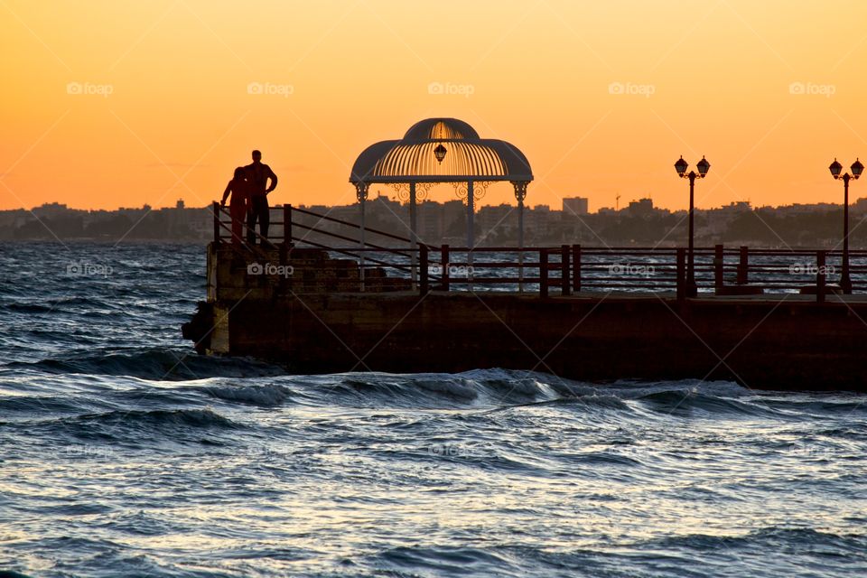 Couple on a pier enjoying the spectacular sunset