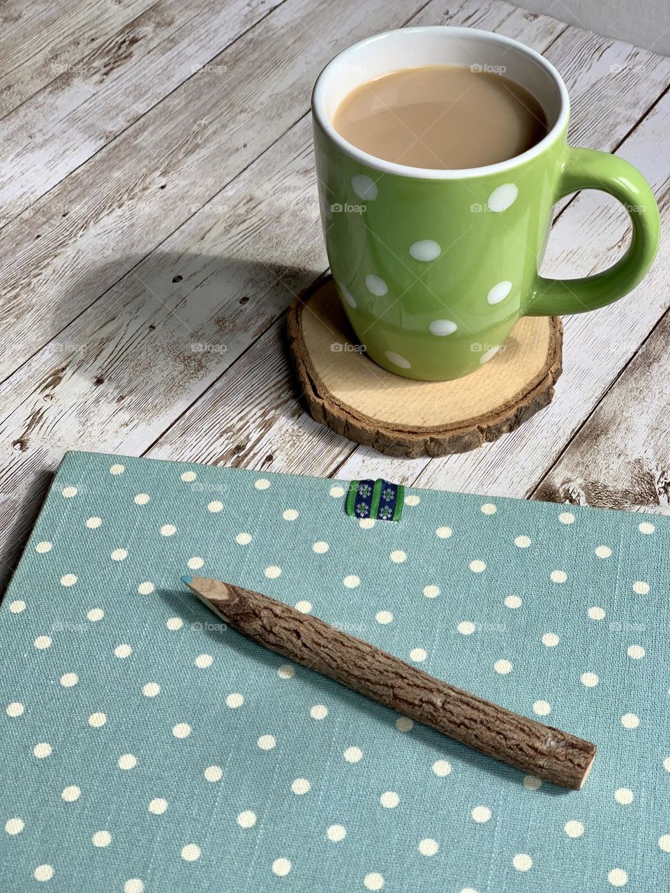 Morning coffee in a green, spotty mug, with a blue notepad covered in white dots