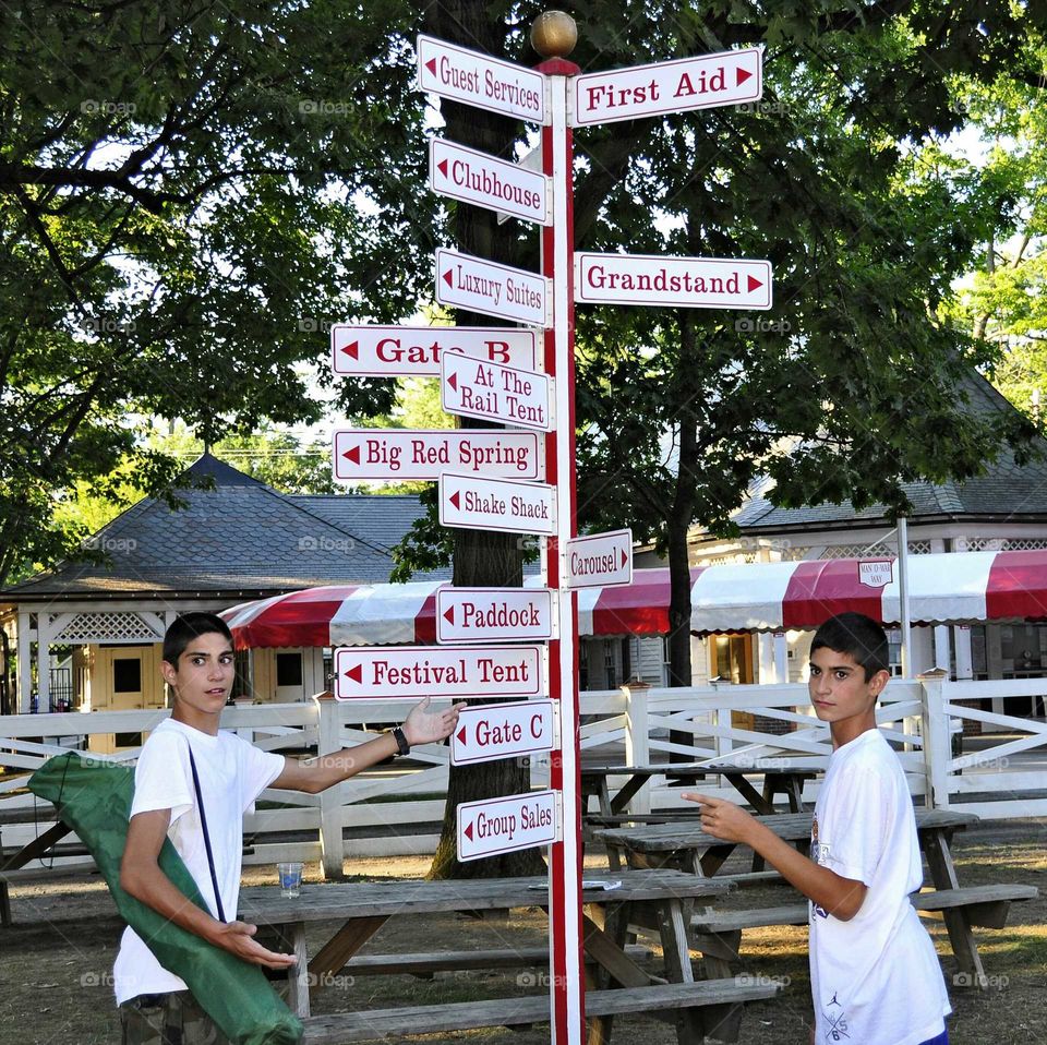 Teenager brother standing near sign board in the park