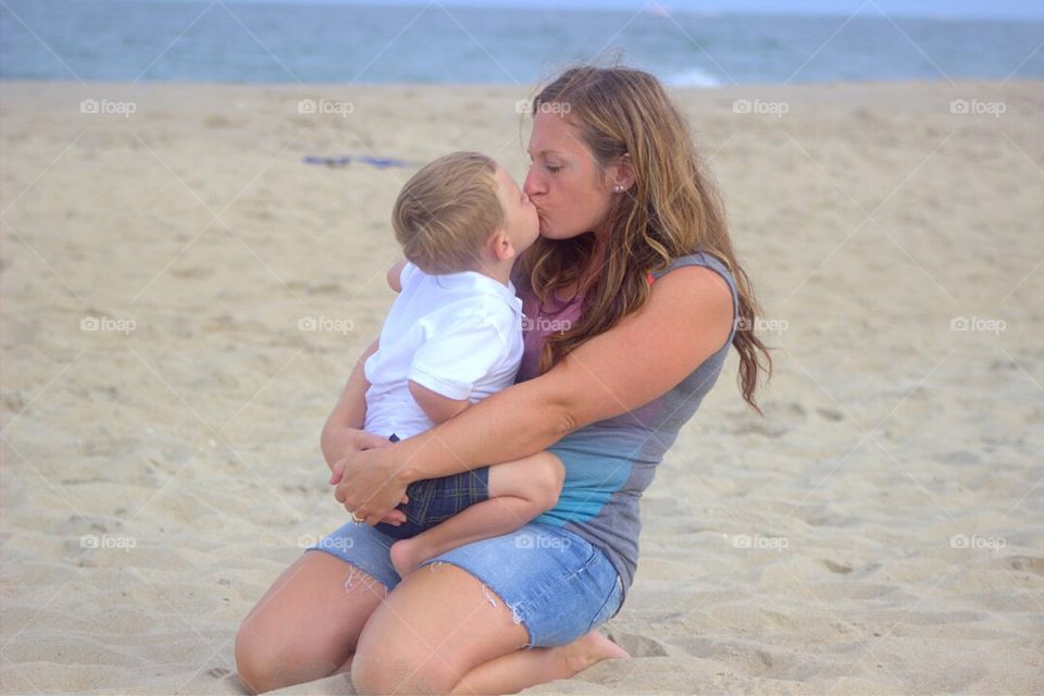 Mother kissing son at beach